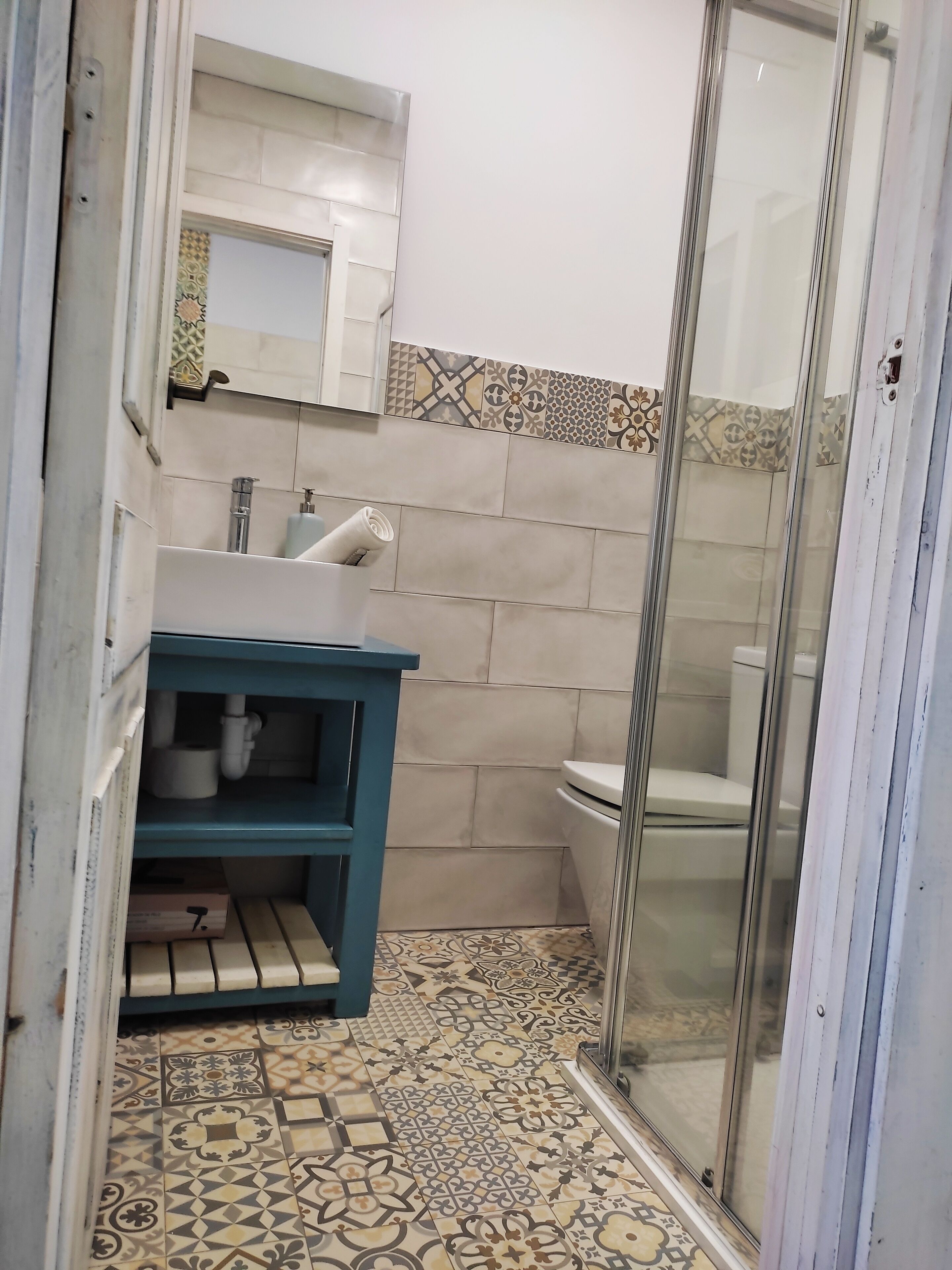 A bathroom with a sink, mirror, toilet, and shower area.