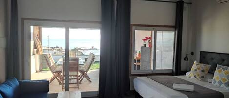 Een slaapkamer met een bed, een bank, een tafel en een balkon met stoelen.