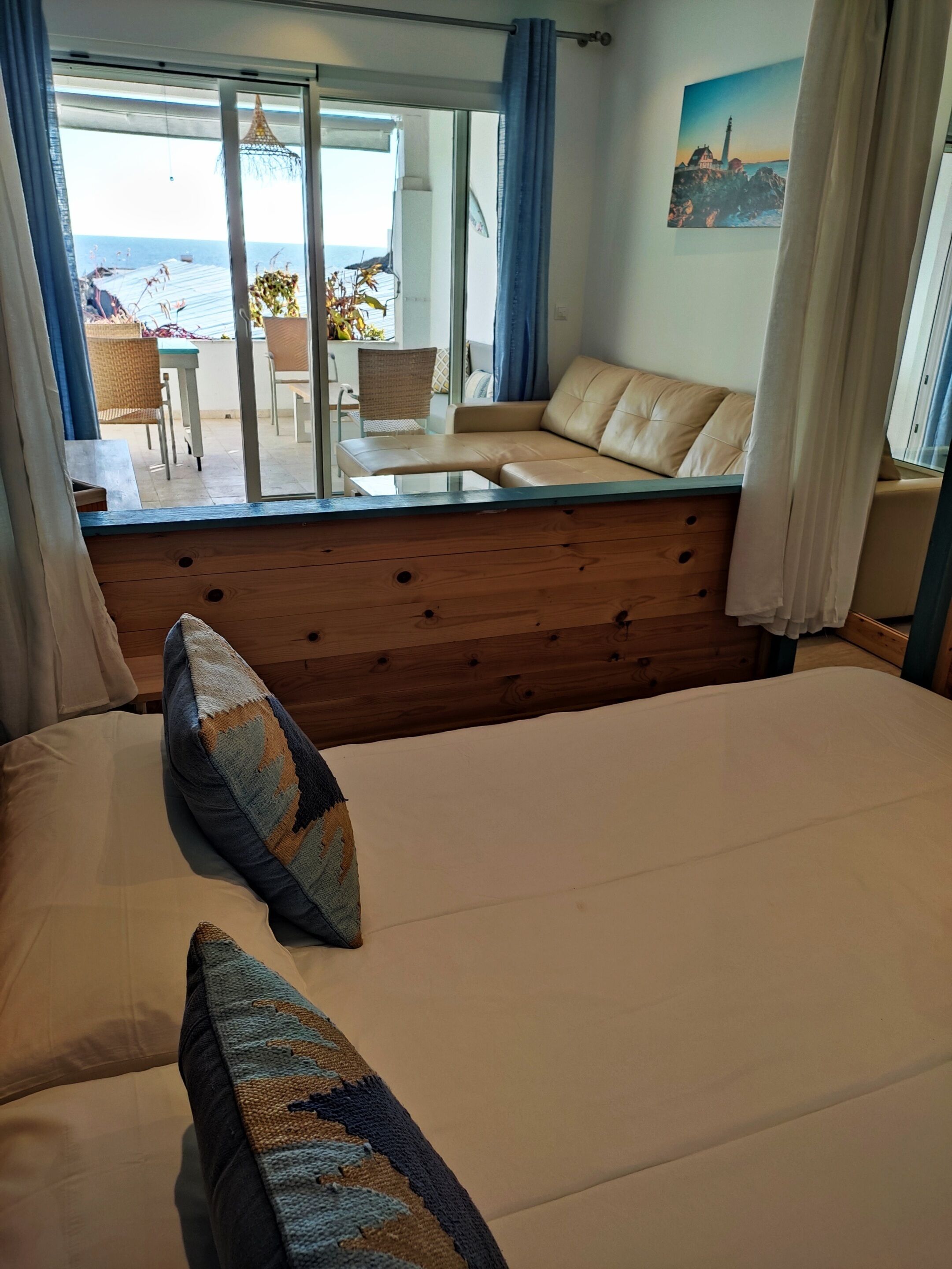 A bedroom with a large bed, a wooden headboard, and a view of the outdoor seating area.