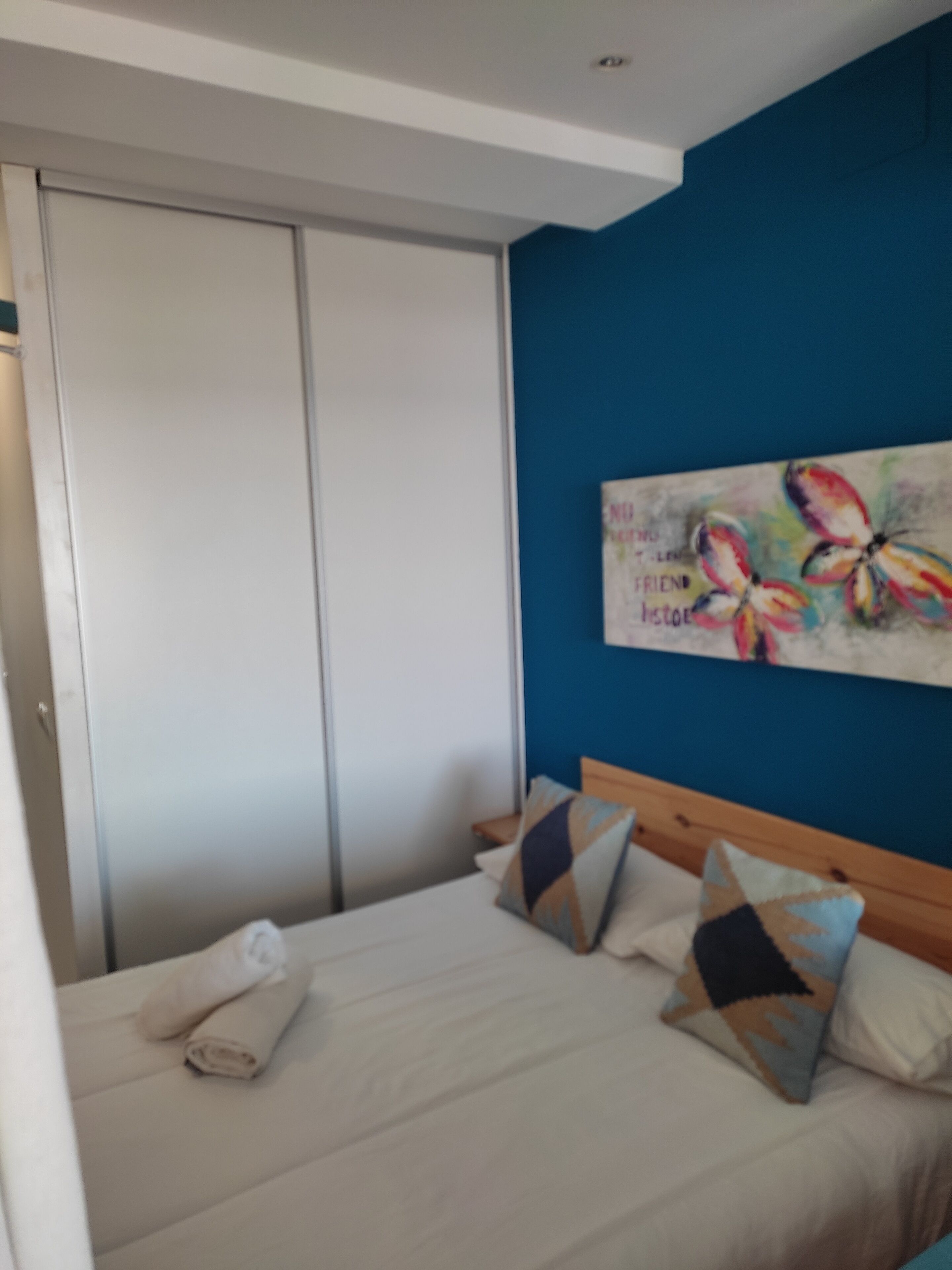 Una camera da letto con un letto, cuscini, un quadro e un armadio.
