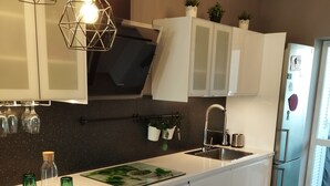 Una cocina moderna con armarios blancos, una isla central e iluminación colgante.