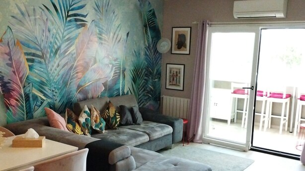 Una sala moderna con un sofá seccional, una mesa de comedor con sillas y un ventanal con vistas al exterior.