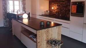 Een moderne keuken met een centraal eiland, een achterwand van steen en een ingebouwde oven.
