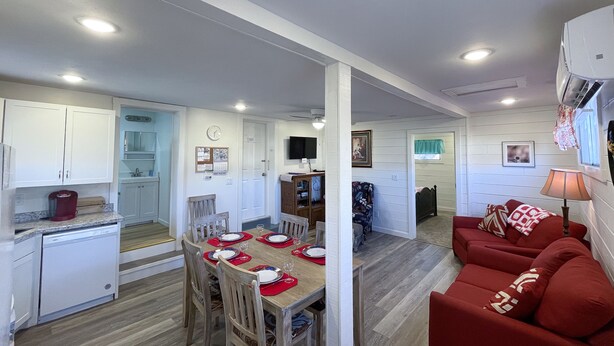 A compact living space with a dining area, kitchen, and a red sofa.