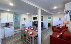 Un espace de vie compact comprenant un coin repas, une cuisine et un canapé rouge.