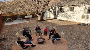A group of people seated around a fire pit in an outdoor patio area with a brick wall and a metal roof.