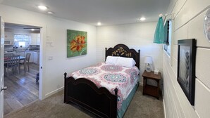 A bedroom with a bed, a nightstand, a wall clock, and a painting.
