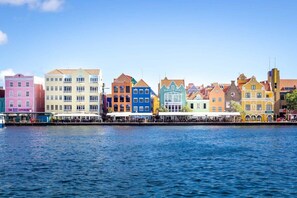 A waterfront with colorful buildings, including a pink building with "The Blue Experience" sign.