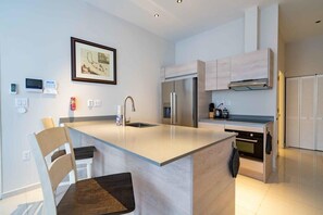 A modern kitchen with a central island, stainless steel appliances, and a framed picture on the wall.