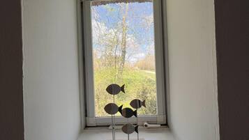 Una ventana pequeña que da a árboles y un cielo despejado.