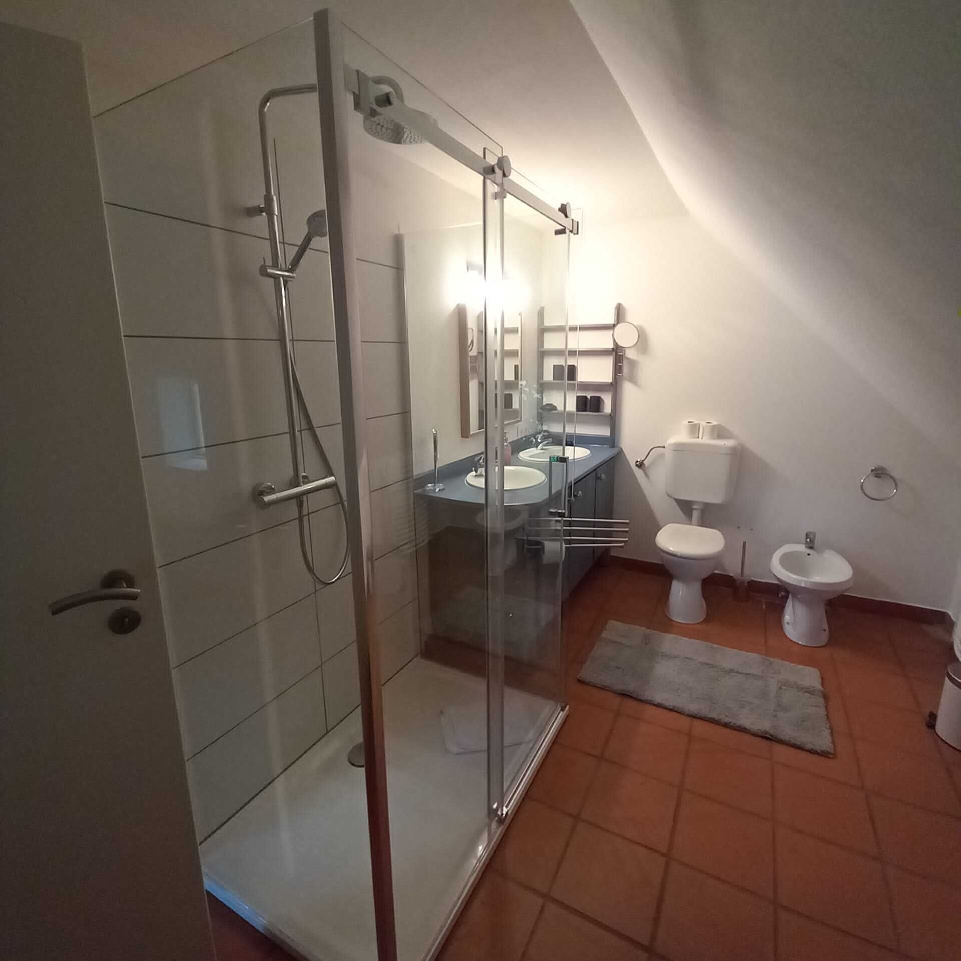 Ein modernes Badezimmer mit Duschkabine, Waschbecken, Toilette und Bidet.