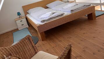 Quarto com cama, mesa de cabeceira, cadeira e vista para o exterior.