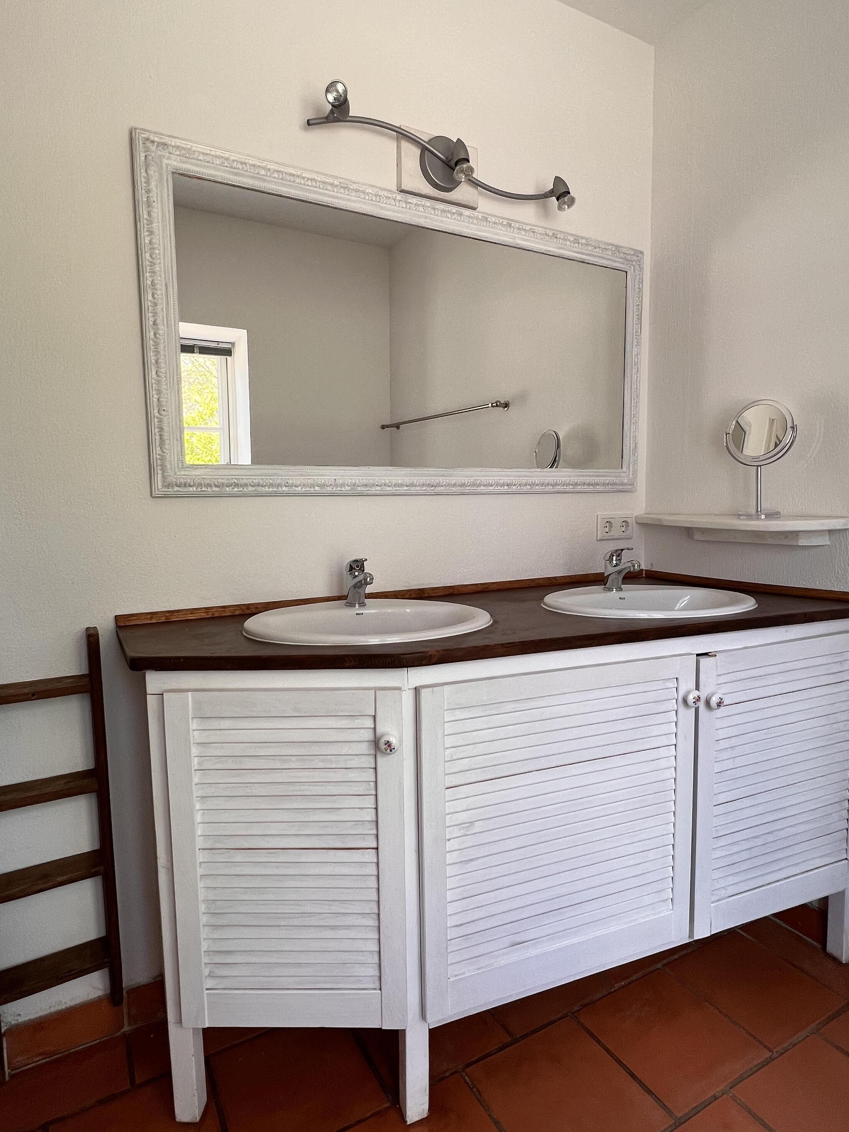 Un bagno con due lavandini, uno specchio grande e un mobile vanitario.