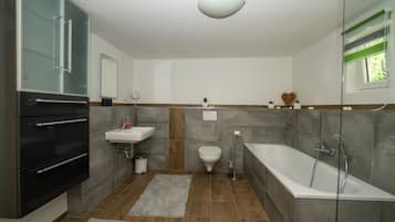 A modern bathroom with a built-in oven, sink, toilet, and bathtub.