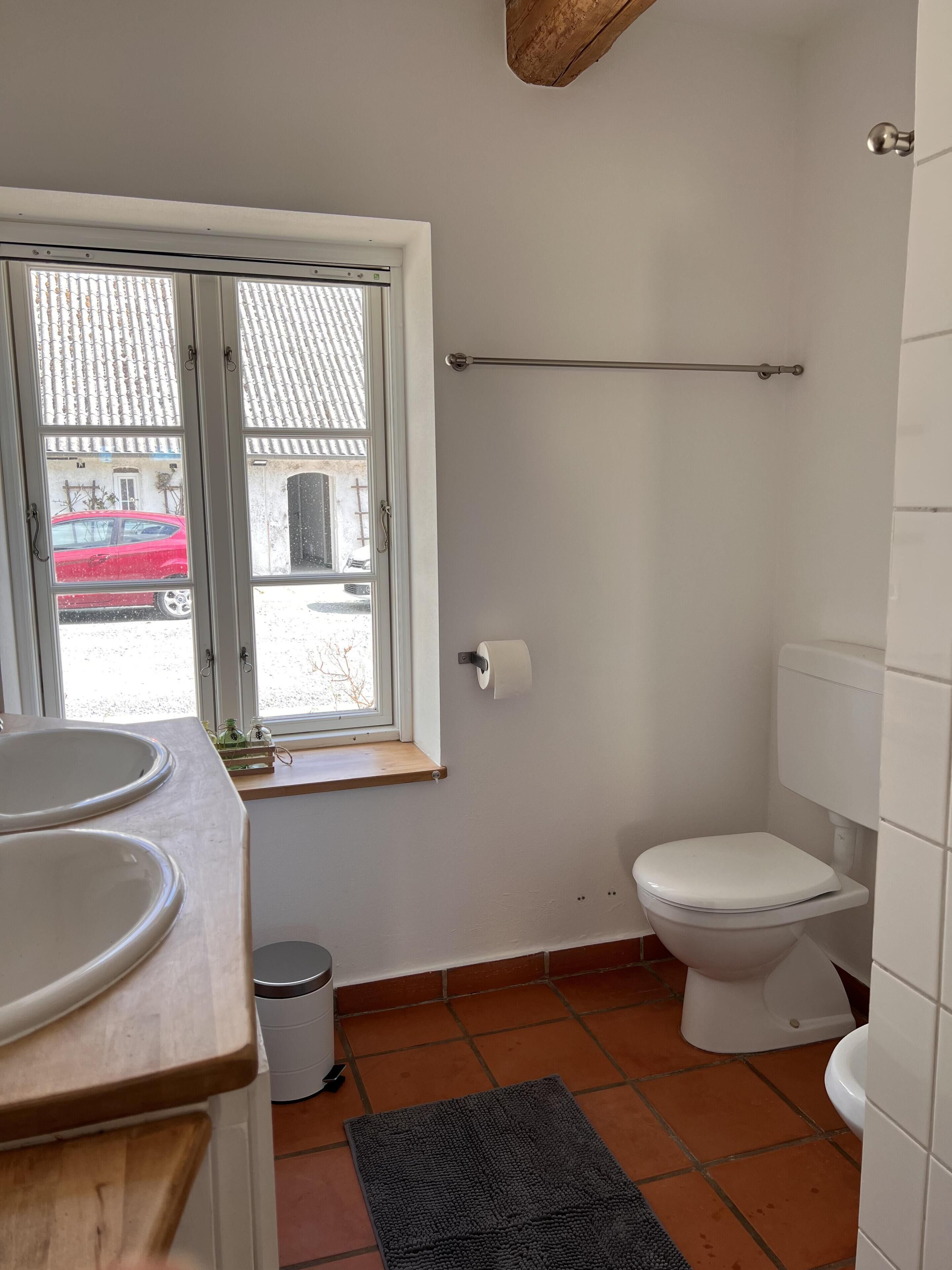 Un baño con inodoro, lavamanos y ventana.