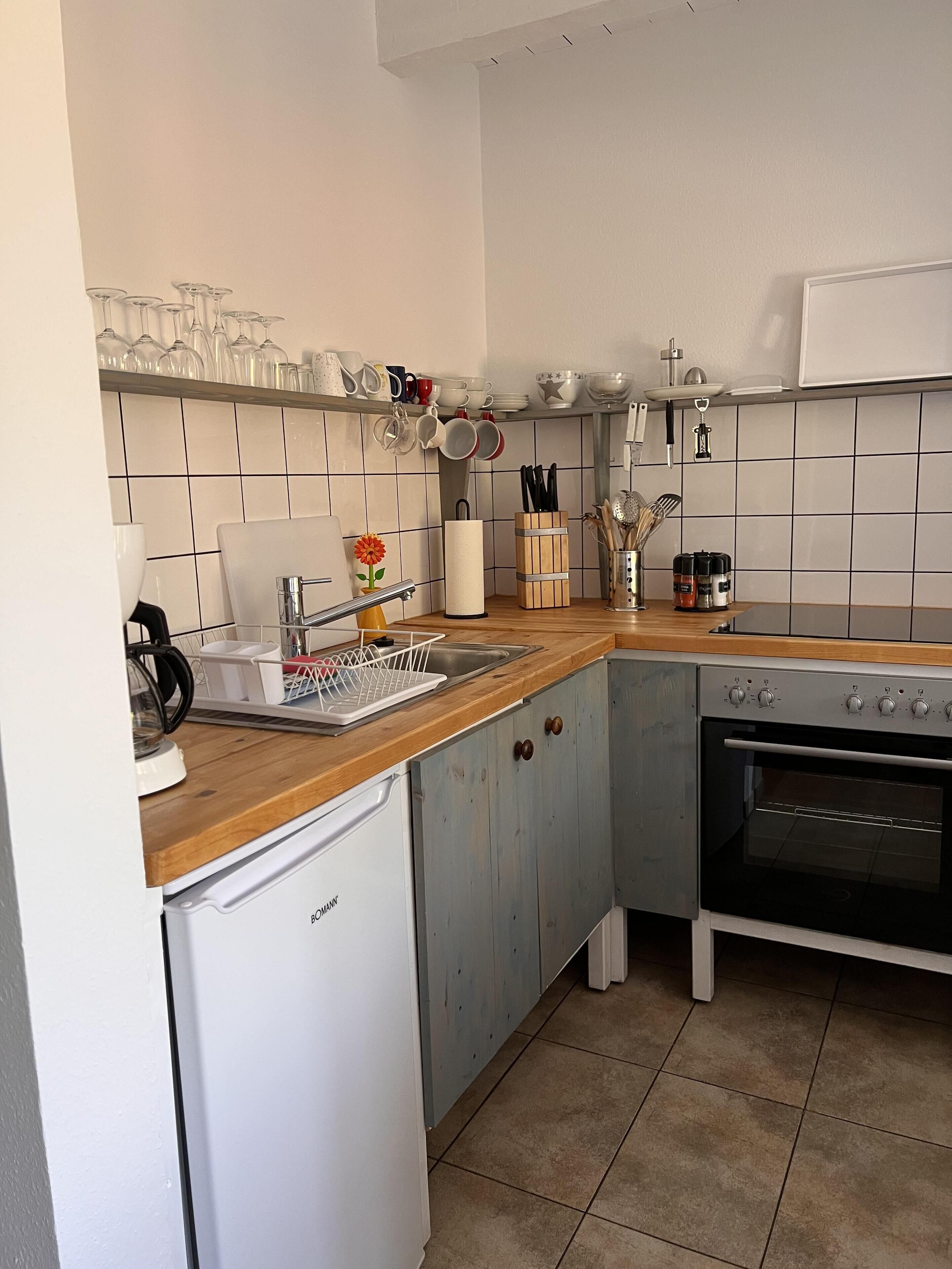 A compact kitchen with a dishwasher, oven, and a wooden countertop.