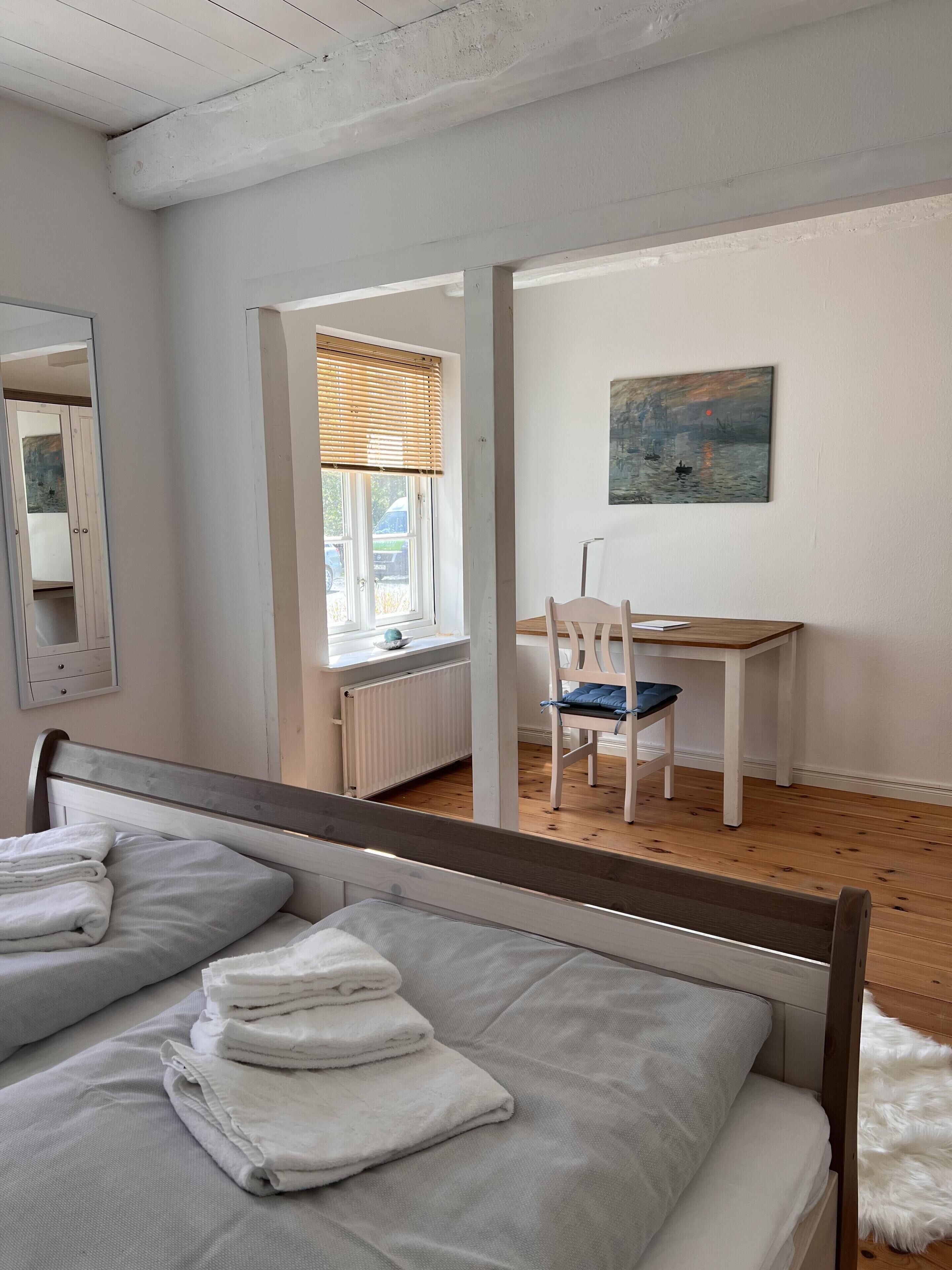 Un dormitorio con una cama, una silla, un escritorio y un cuadro en la pared.