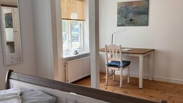 Un dormitorio con una cama, una silla, un escritorio y un cuadro en la pared.