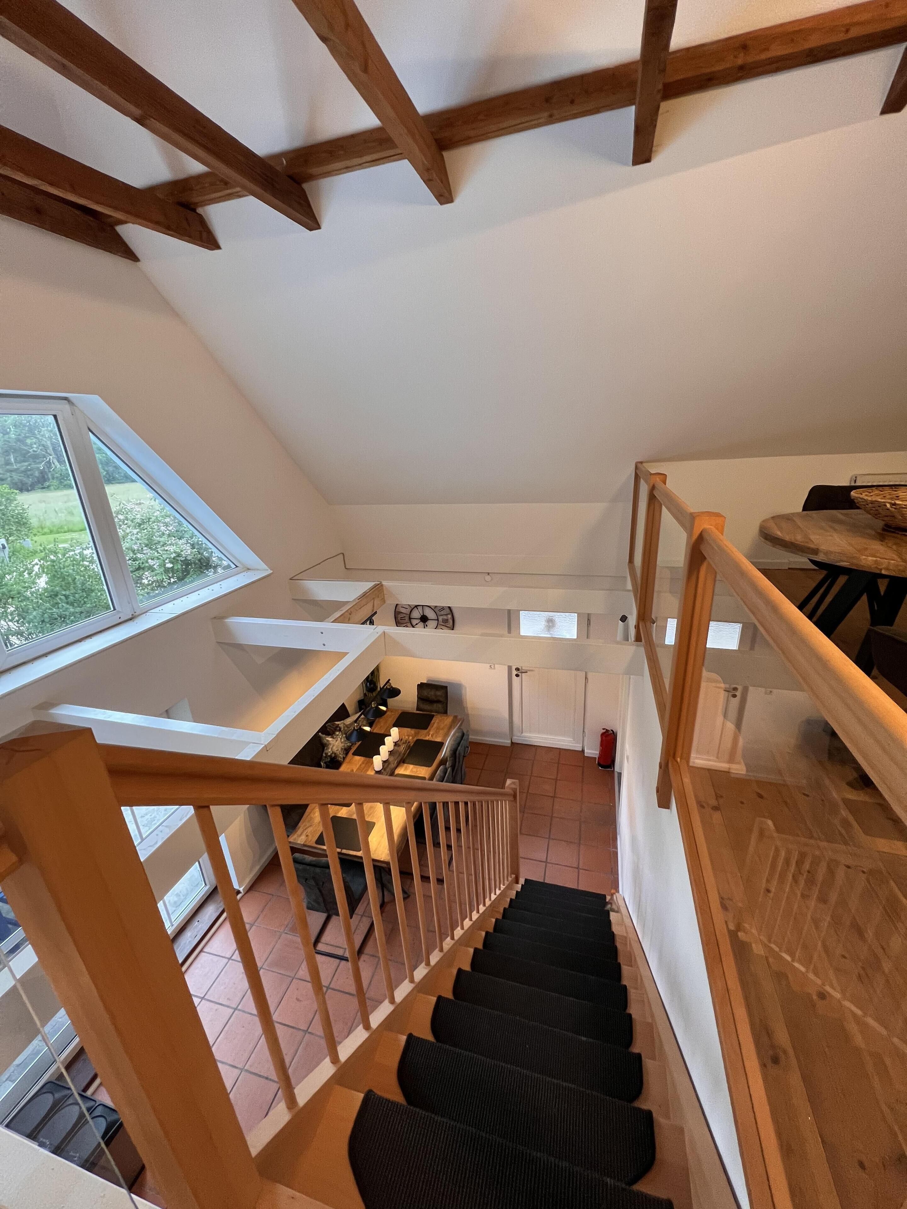A staircase with wooden railings leading to a dining area with a table and chairs.