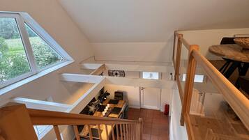 A staircase with wooden railings leading to a dining area with a table and chairs.