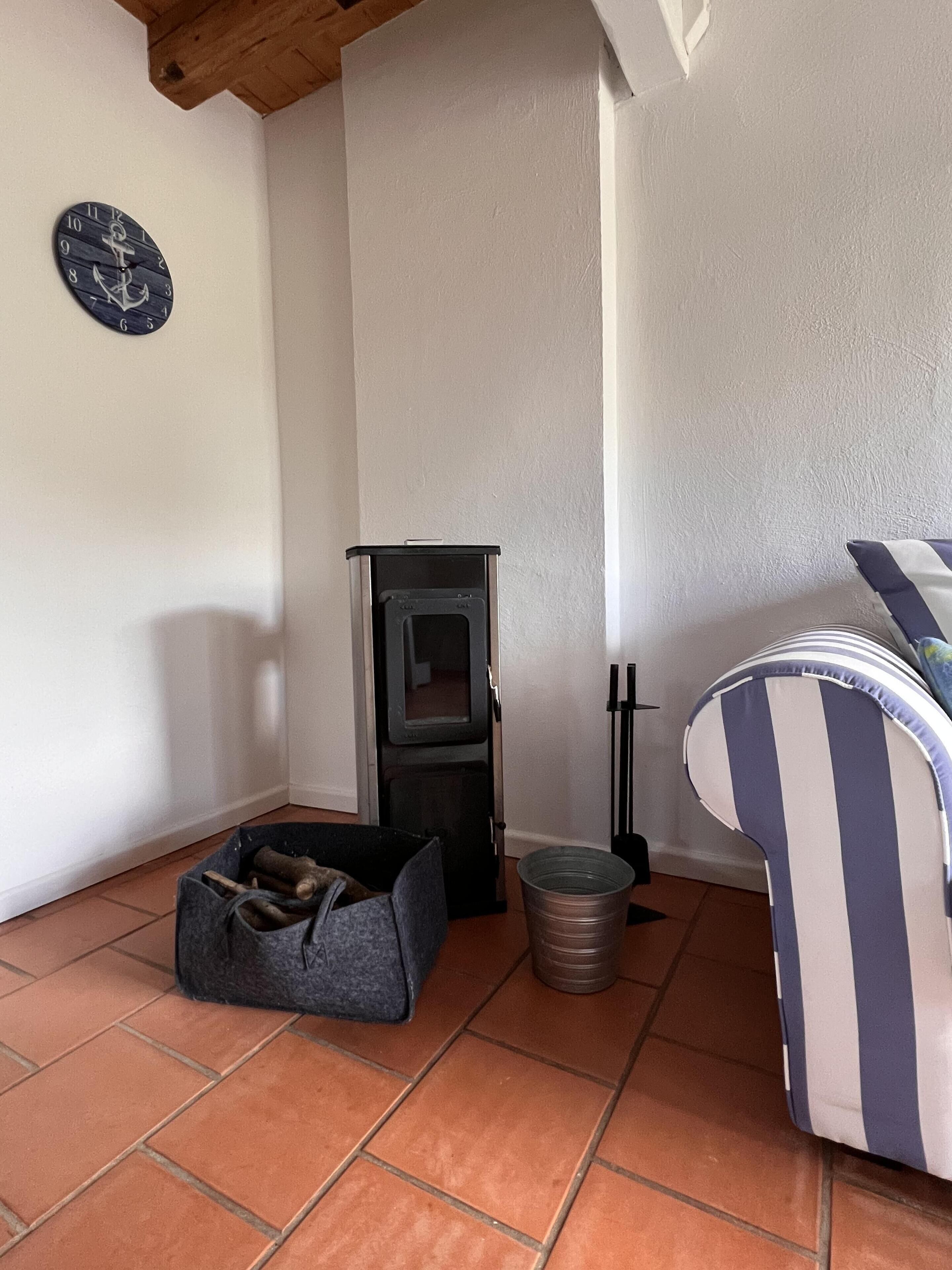 Ein gemütliches Zimmer mit Kamin, einer Wanduhr und einem Streifenstuhl.