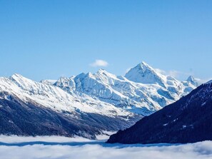 A mountain landscape with snow-covered peaks and a valley below.