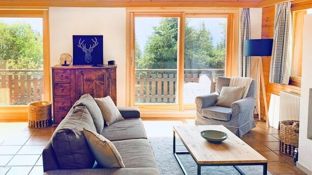 Ein gemütliches Wohnzimmer mit einer Couch, Sesseln, einem Couchtisch und einem Kamin.