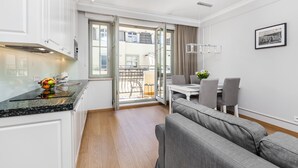 A modern kitchen with white cabinets, a granite countertop, and a dining area with a table and chairs. - Happy Stay Sopot Monte Cassino 40 (Sopot)
