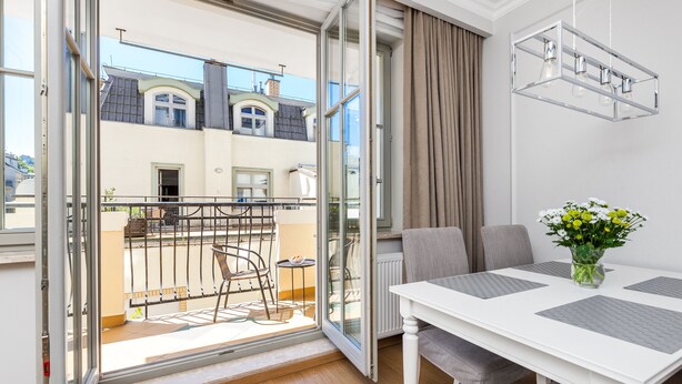 A modern apartment with a balcony, a dining area with a table and chairs, and a clear view of neighboring buildings. - Happy Stay Sopot Monte Cassino 40 (Sopot)