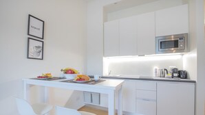 Une cuisine moderne avec des meubles blancs, un four à micro-ondes en acier inoxydable et un espace repas aménagé sur le comptoir.
