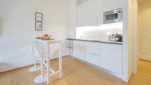 Une cuisine moderne avec des meubles blancs, un four à micro-ondes, une bouilloire et un espace dédié au petit-déjeuner sur le comptoir.