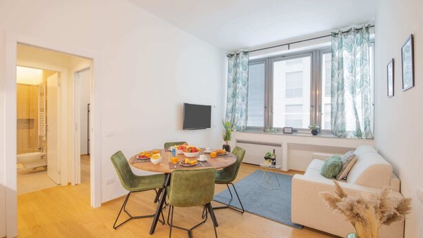 Een moderne woonkamer met een eethoek, een bank en een televisie.