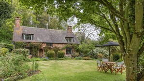 A brick house with a garden, a lawn, and a patio with chairs. - Saint Pancras Chapel (Watchet)