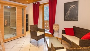 A cozy room with wicker furniture, a glass door leading to a balcony, and a bear painting on the wall. - Chalet, wifi, sauna, balcony, parking, tv, ski locker, 230m², Peisey-Vallandry (Peisey-Nancroix)