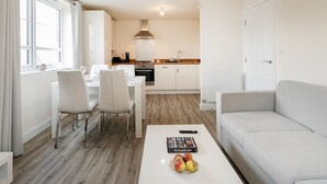 Un appartement moderne et bien éclairé, comprenant un coin repas, une cuisine et un espace de vie.