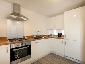 A modern kitchen with white cabinets, a stainless steel range hood, a built-in oven, and a wooden countertop. - Luxurious 2-Bed Nottingham Retreat with Parking - Pass the Keys (Nottingham)