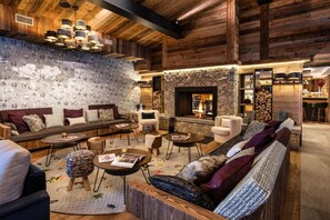 A cozy living room with a fireplace, wooden walls, and a patterned wallpaper. - Wifi, fitness, swimming pool, sauna, hammam, balcony, fireplace or stove, tv, ski locker, 60m² (Val-d'Isère)
