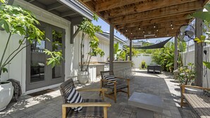 An outdoor patio with wicker furniture, a stone floor, and a wooden pergola.