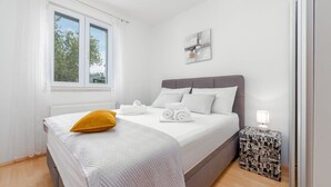 A neatly made bed with white linens and a mustard-colored pillow, a bedside lamp, and a small side table with a patterned cloth. - Villa Trkalj Zadarvillas (Policnik)