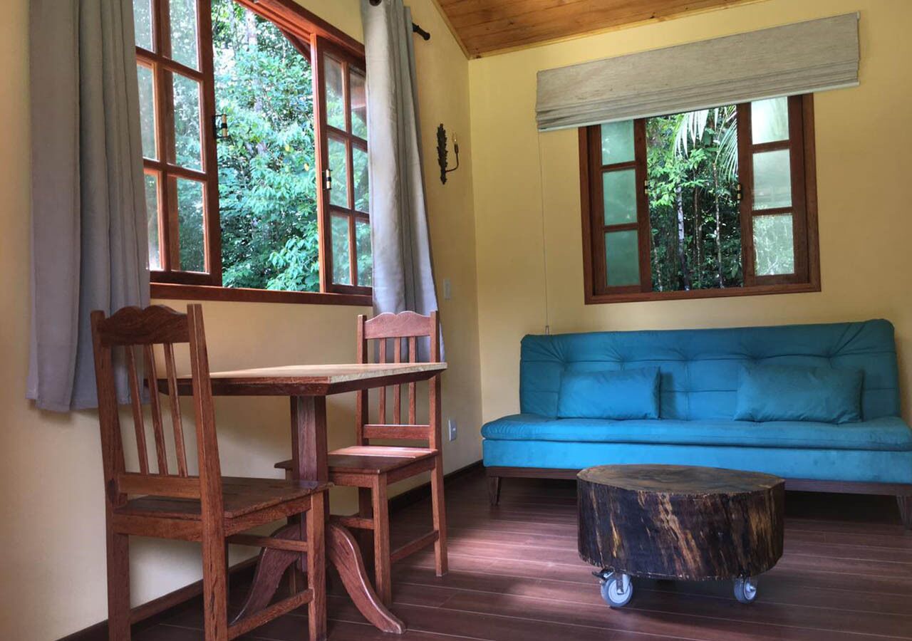 A room with a wooden table and chairs, a blue sofa, and a round wooden coffee table with wheels.
