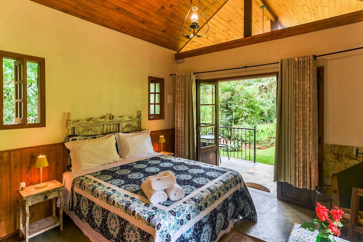 Une chambre avec un grand lit, un plafond en bois et une vue sur la verdure.