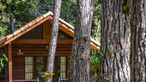 A wooden cabin with a sloped roof, surrounded by trees. - Amadamata Refúgio Ecológico (Nova Friburgo)