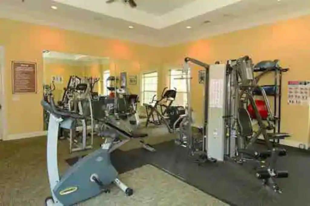 Ett gym med konditionsmaskiner, styrketräningsutrustning och speglar på väggarna.