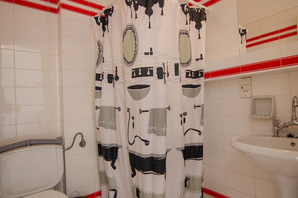 A bathroom with a toilet, a sink, and a shower curtain with a black and white pattern.