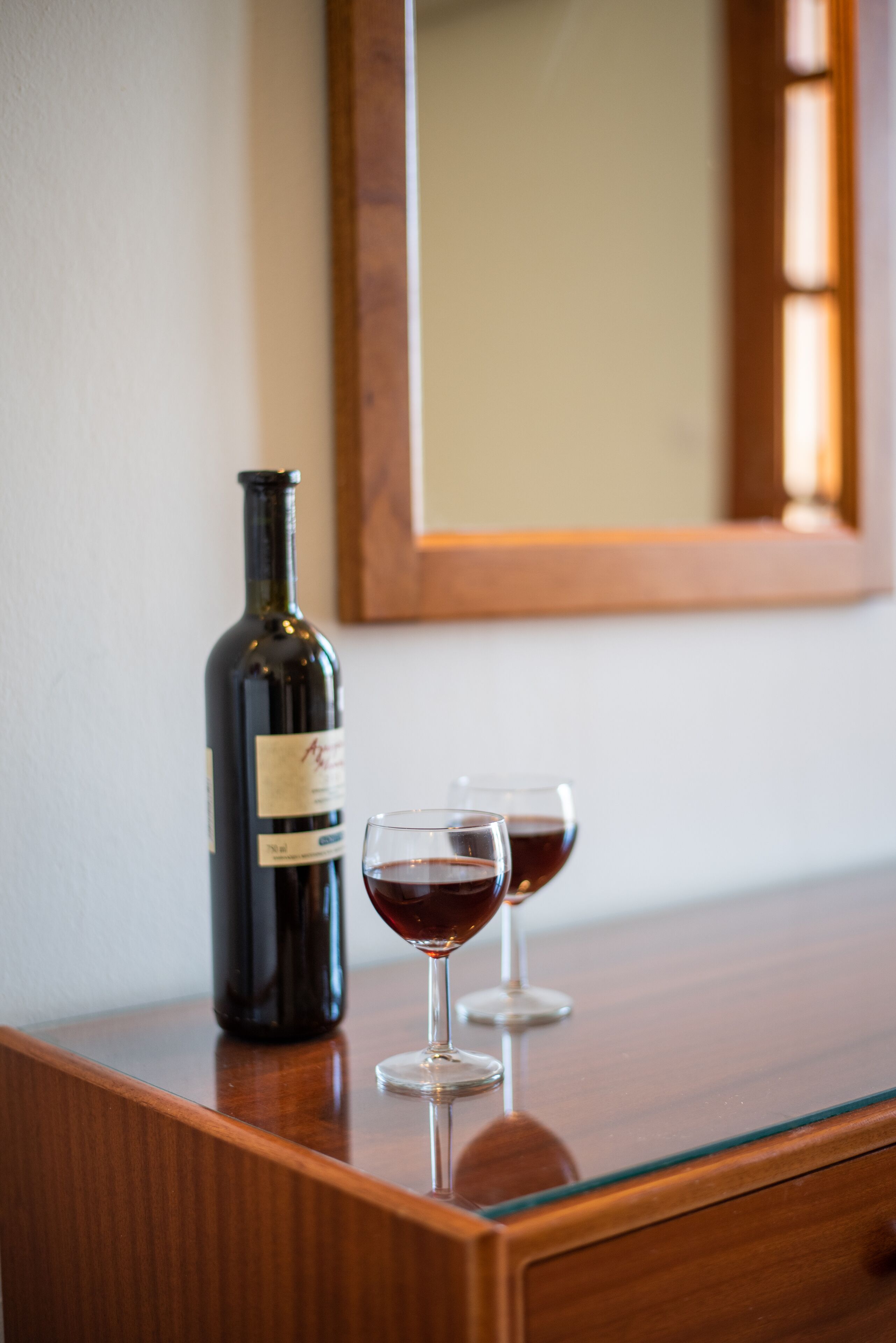 Una mesa de madera con una botella de vino y dos copas de vino.