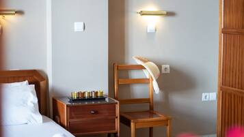 Habitación de hotel con cama de madera, una mesita de noche con bandeja de velas, una silla de madera y un armario.