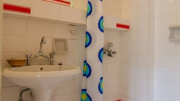 A bathroom with a white sink, a shower with a blue and green shower curtain, and red and white tiled walls.