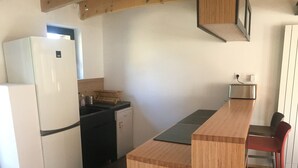 Cocina compacta con refrigerador, lavavajillas y encimera de madera.