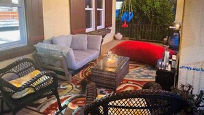 Un espace patio accueillant avec un canapé, des fauteuils et une balançoire suspendue.