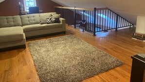 Un salon confortable avec un canapé, un tapis et un escalier doté d’une rampe.